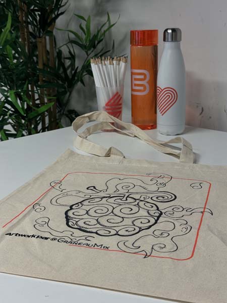 Table exposant des produits Bellecour École, incluant des bouteilles, des crayons et un totebag avec une illustration personnalisée